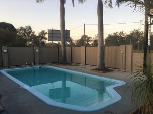 a swimming pool with two palm trees next to a fence at Bororen Motel in Bororen