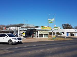 un'auto bianca parcheggiata di fronte a un distributore di benzina di Wattle Tree Motel a Cootamundra