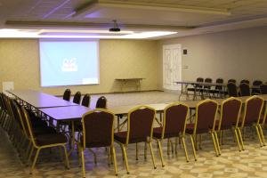 una sala de conferencias con mesas, sillas y una pantalla en The Corner Hotel en Sincan