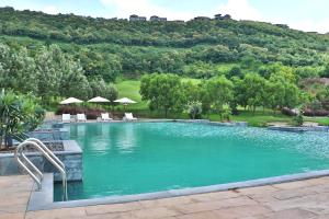 uma grande piscina com uma montanha ao fundo em Oxford Golf Resort em Pune