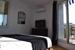 a bedroom with a bed and a tv and a window at Appartement terrasse vue mer / nice in Nice
