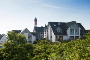 a group of houses with a lighthouse in the background at Apartmenthotel am Leuchtturm in Hörnum
