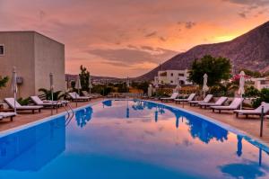uma piscina num resort com cadeiras e um pôr-do-sol em Phevos Villa em Perissa