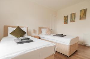 two beds in a room with white walls and wooden floors at M9 Falkirk Apartment in Falkirk