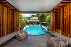 an indoor swimming pool in a house with two chairs at Karon Beach Pool Villa - Sha Extra Plus in Karon Beach