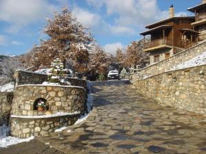 a stone wall with a snow covered stairway next to a building at Efharis Filoxenon in Feneos