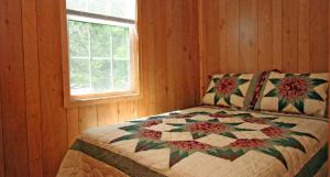 Robin Hill Camping Resort Premium Cottage 1 في Lenhartsville: غرفة نوم بها لحاف على سرير مع نافذة
