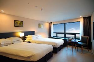 a hotel room with two beds and a table and a window at Best Western Jeju Hotel in Jeju +100 photos