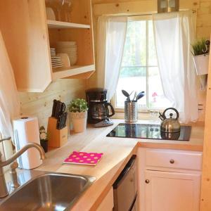 una pequeña cocina con fregadero y ventana en Leavenworth Camping Resort Tiny House Hanna en Leavenworth