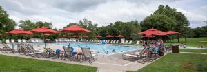 a swimming pool with chairs and red umbrellas at Circle M Camping Resort Yurt in Lancaster