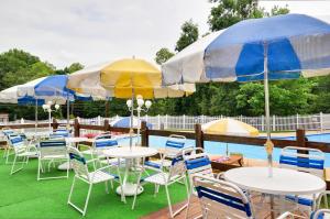 um grupo de mesas e cadeiras com guarda-sóis ao lado de uma piscina em Sun Valley Campground Cottage 4 em Maple Grove Park