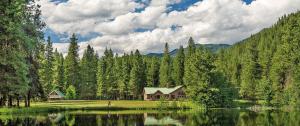 a house next to a lake in front of a forest at Leavenworth Camping Resort Tiny House Adeline in Leavenworth