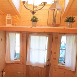 Leavenworth Camping Resort Tiny House Hanna في ليفنوورث: غرفة بها نافذتين في منزل خشبي