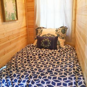 a bedroom with a bed with a blue and white comforter at Leavenworth Camping Resort Tiny House Adeline in Leavenworth