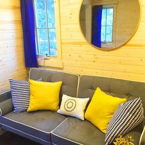 um sofá com almofadas amarelas e brancas em Leavenworth Camping Resort Tiny House Belle em Leavenworth