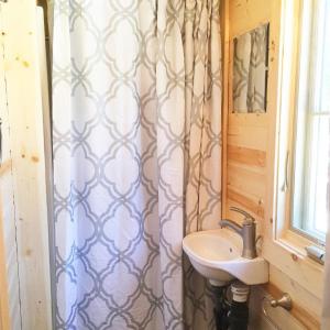 baño con lavabo y cortina de ducha en Leavenworth Camping Resort Tiny House Adeline en Leavenworth
