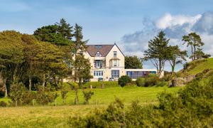 une grande maison au-dessus d'un champ herbeux dans l'établissement Gwesty Gadlys Hotel, à Baie de Cemaes