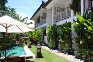 a resort with a swimming pool and an umbrella at Papaya Guesthouse in Canggu
