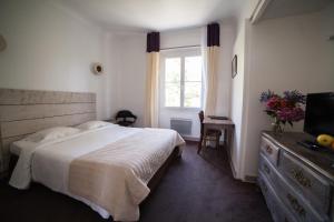 a bedroom with a bed and a television and a window at Hotel Saint Paul in Noirmoutier-en-l'lle