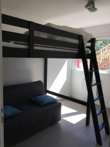 a bunk bed with a couch in a room at Villa Coquelicot in Lacanau