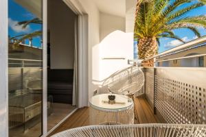 a balcony with a tub and a palm tree at Apartaments Cales de Ponent in Ciutadella