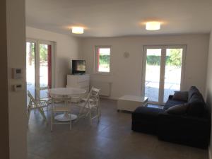 a living room with a couch and a table and chairs at Villa Coquelicot in Lacanau