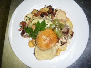 a white plate of food with grapes and meat at Hotel Restaurant du Lion d'Or in Château-Chinon