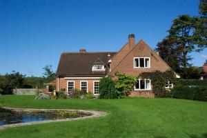a large brick house with a pond in front of it at Mayertorne Cottage in Aylesbury