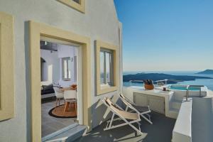 a balcony with chairs and a table and a pool at Aroma Suites in Fira
