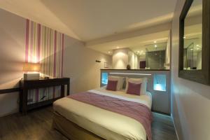 a hotel room with a bed and a mirror at Hotel-Restaurant Lann Roz / Côte Cuisine in Carnac