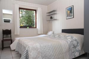 a white bedroom with a bed and a window at Ferienhaus am Maibüsch - rollstuhlgerecht in Ulmen