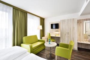 a hotel room with a bed and two chairs and a table at Novina Sleep Inn Herzogenaurach in Herzogenaurach