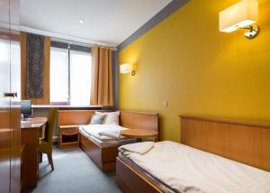 a hotel room with two beds and a desk at Hotel Restauracja Tawerna Gliwice in Gliwice