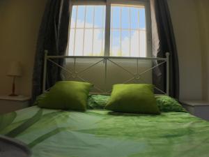 a bed with two green pillows in front of a window at Apartamentos Club del Mar San Juan Beach in Alicante