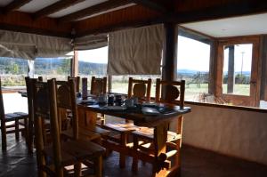 - une salle à manger avec une table, des chaises et des fenêtres dans l'établissement Ruta 71, à Trevelín