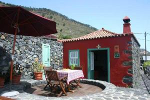 a red house with a table and an umbrella at Casa Rural La Caldera in Fuencaliente de la Palma