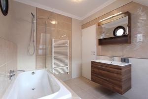 a bathroom with a tub and a sink and a mirror at Good Luck Apartment in Hévíz +11 photos