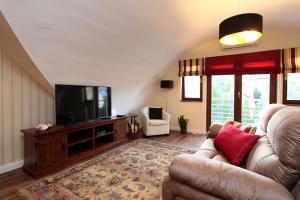 a living room with a couch and a flat screen tv at Good Luck Apartment in Hévíz