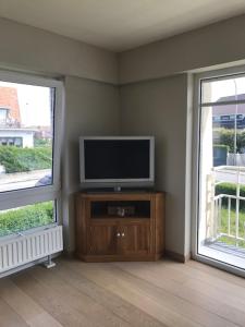a living room with a television and two windows at Wenduine-strand in Wenduine