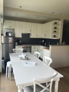 a kitchen with white cabinets and a white table and chairs at Wenduine-strand in Wenduine