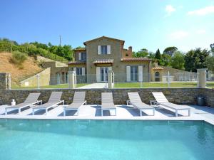 コルトーナにあるLuxurious Villa in Cortona Italy with Swimming Poolの背景に家があるプール(椅子付)