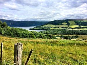 a fence in a field with a view of a lake at Drumbuie Farm B&B in Drumnadrochit