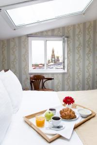 ein Tablett mit Frühstückszutaten auf einem Bett mit Fenster in der Unterkunft Hotel Moyka 5 in Sankt Petersburg