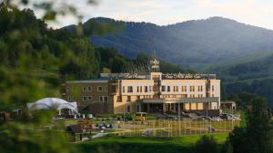 a large building with a clock tower in front of a mountain at Altai Palace Hotel in Manzherok