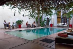 um grupo de pessoas sentadas ao redor de uma piscina em Riad Charaï em Marrakech