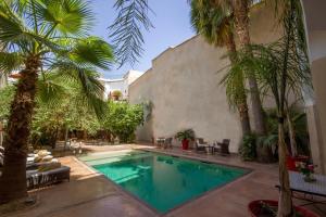 a swimming pool in a yard with palm trees at Riad Charaï in Marrakech