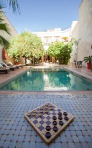 a chess board sitting next to a swimming pool at Riad Charaï in Marrakesh