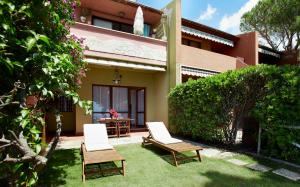 a yard with two chairs and a table in front of a house at Pinus Village Sea Front Apartment in Pula +5 photos