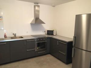 a kitchen with black cabinets and a stainless steel refrigerator at Villa Coquelicot in Lacanau