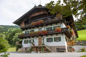 una casa en las montañas con flores en los balcones en Ferienwohnung Lehenhof, en Hopfgarten im Brixental